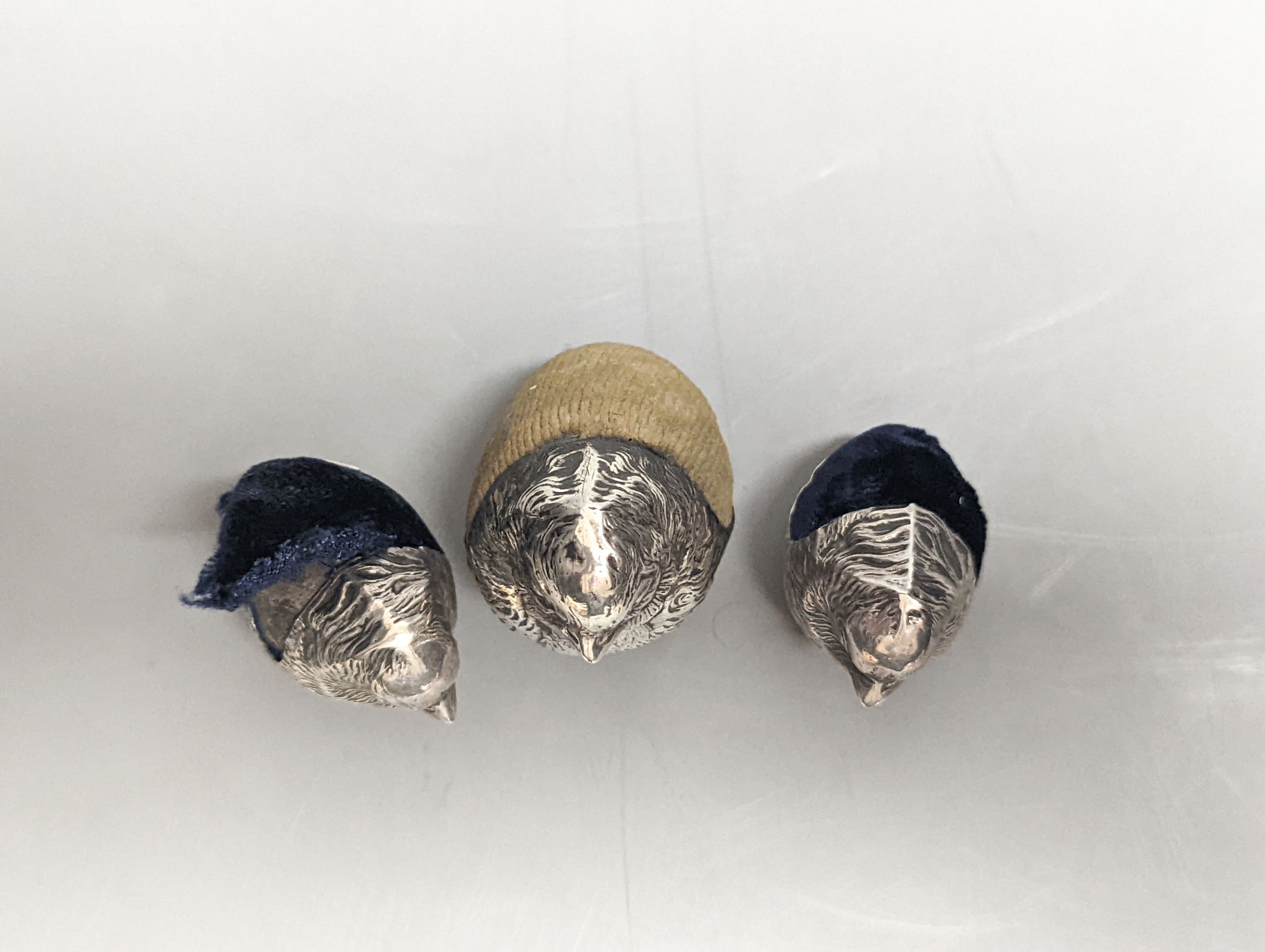 A suite of three Edwardian novelty silver mounted chick pin cushions, by Sampson Mordan & Co, Chester, 1907, height 43mm(1) & 33mm(2).